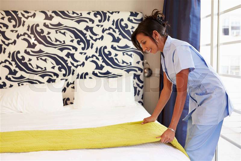 Maid Tidying Hotel Room And Making Bed, stock photo