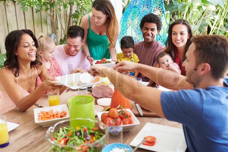 Group Of Families Enjoying Outdoor Meal At Home, stock photo