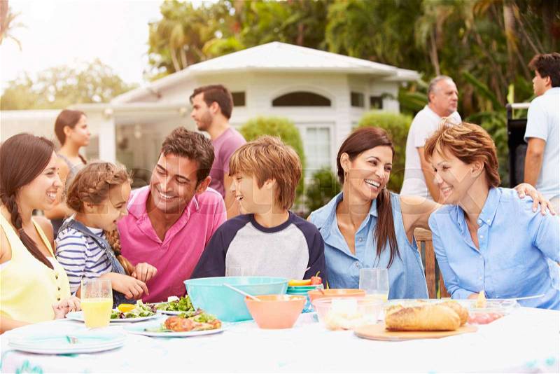 Multi Generation Family Enjoying Meal In Garden Together, stock photo