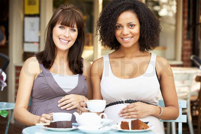 Pregnant women sitting outside café, stock photo