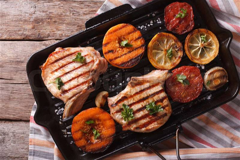 Grilled pork and pumpkin on a grill pan. Horizontal close-up view from above, rustic style , stock photo
