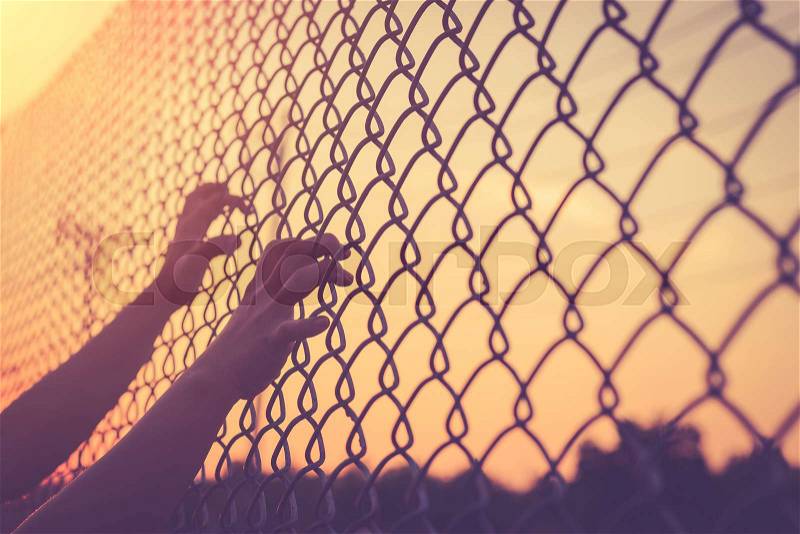 Hand holding on chain link fence, Vintage filter effect, stock photo