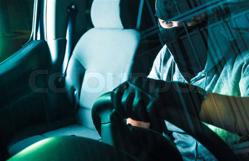 Auto Theft Carjacking. Young Caucasian Male Carjacker in Black Mask Driving Stolen Car. Motor Vehicle Theft Concept Photography. Grand Auto Theft, stock photo