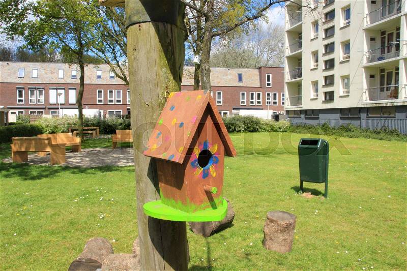 Selfmade striking bird house in the residential area with terraced house and an apartment building in spring in the village, stock photo