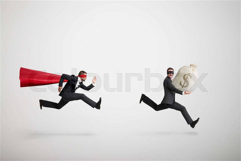 Thief stole the bag with money and running away from superman over light grey background, stock photo
