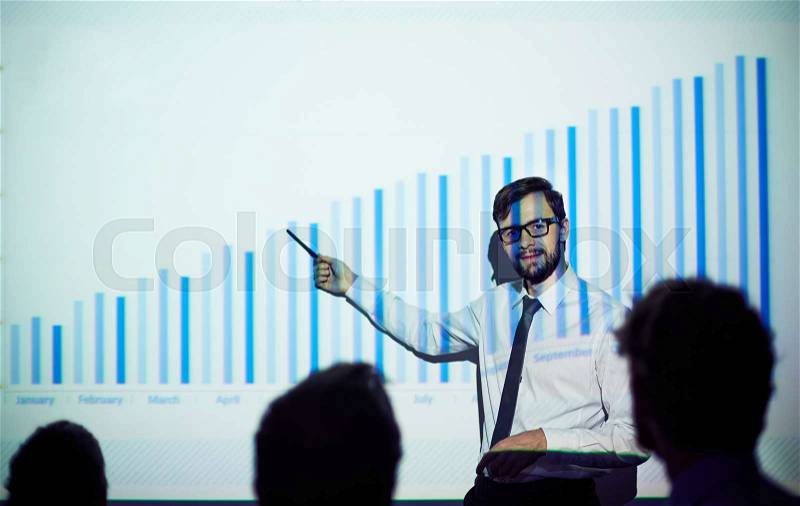 Confident male teacher presenting report of progress on the wall, stock photo
