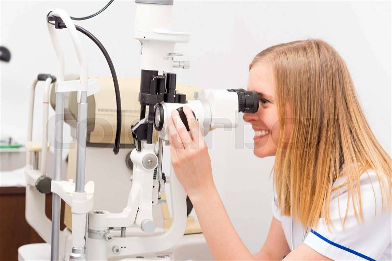 Young ophtalmologist adjusting optical device professionally, stock photo