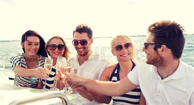 Vacation, travel, sea, friendship and people concept - smiling friends with glasses of champagne on yacht, stock photo