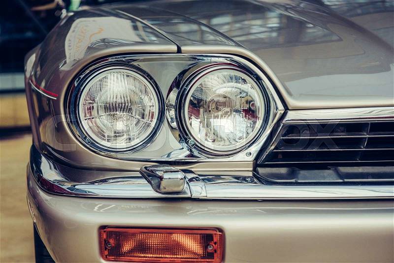 A closeup of the headlights and front bumper on a vintage automobile, stock photo