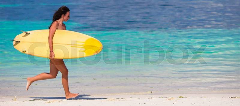 Happy young surf woman runing at the beach with a surfboard, stock photo