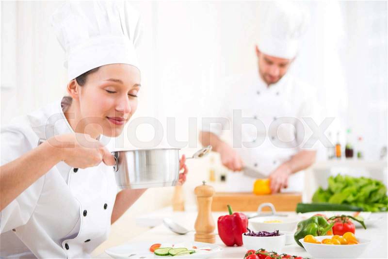 View of a Young attractive professional chef tasting sauce, stock photo