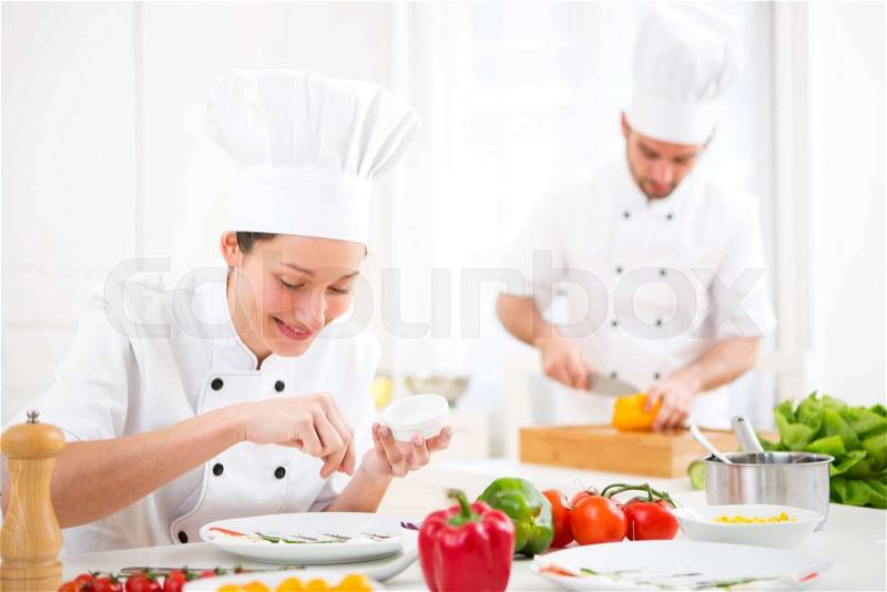 View of a Young attractive professional chef cooking in his kitchen , stock photo