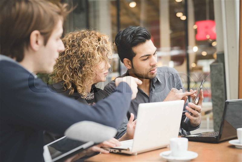 Multiracial business people working connected with technological devices at the bar, stock photo
