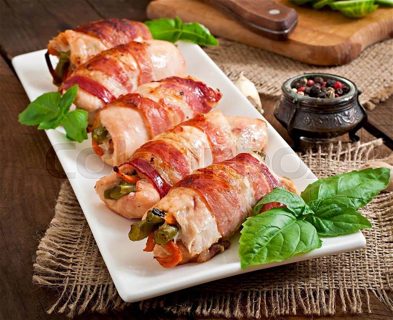 Delicious chicken rolls stuffed with green beans and carrots wrapped in strips of bacon, stock photo