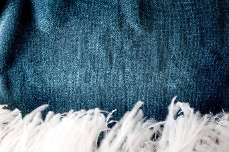 Dark blue shade fabric background with white soft feather on foreground, stock photo