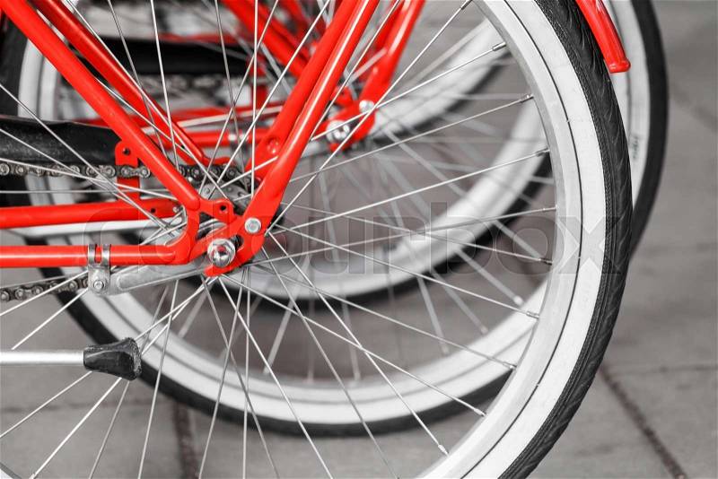 Parked red street bicycles for rent, rear wheels fragment, selective focus with shallow DOF, stock photo