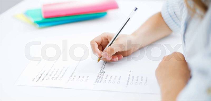 Education, children and school concept - little student girl taking test, stock photo