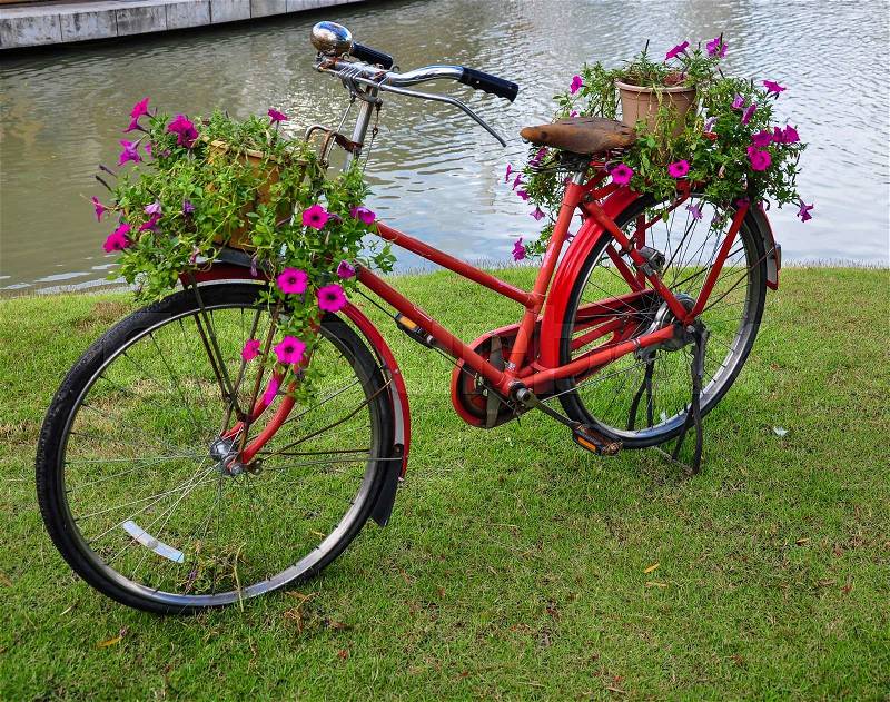 Red painted bicycle with a bucket of colorful flowers, stock photo