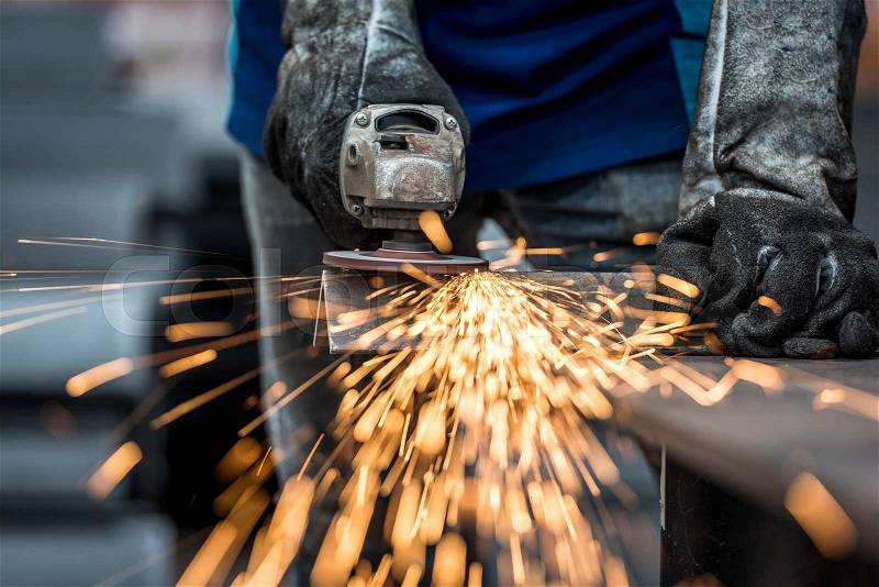 Industrial worker cutting metal with many sharp sparks, stock photo