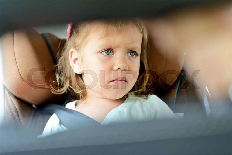 Sad little girl in the car seat, stock photo