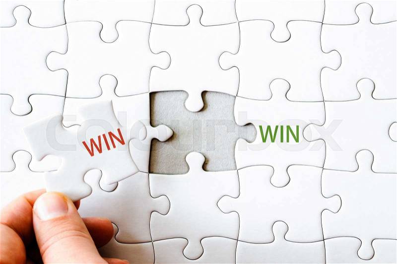 Hand with missing jigsaw puzzle piece completing the wordS WIN WIN. Business concept image for completing the final puzzle piece, stock photo