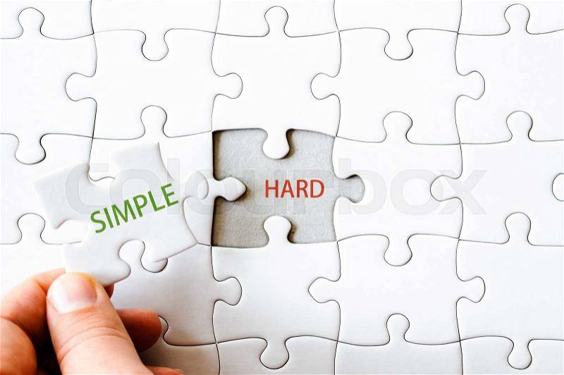 Hand with missing jigsaw puzzle piece. Word SIMPLE, covering the text HARD. Business concept image for completing the final puzzle piece, stock photo