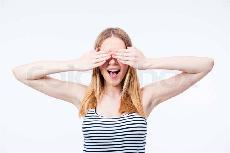 Young happy woman covering her eyes over gray background, stock photo