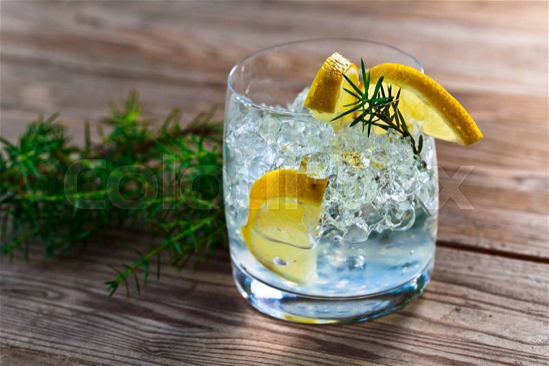 Gin and tonic with lemon and ice on wooden table, stock photo