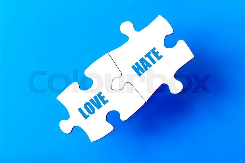 Connected puzzle pieces with words LOVE and HATE isolated over blue background, with copy space available. Business concept image, stock photo