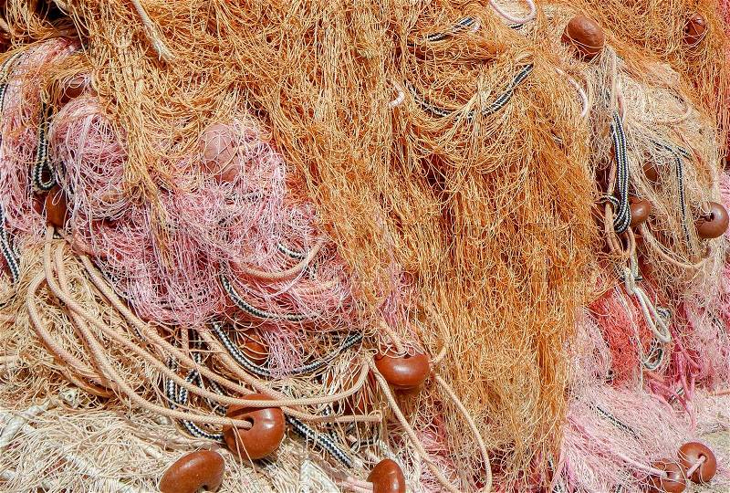 Pile of fishing nets on a quay, warm colors, chords and buoy well visible; perfect for background, screen saver or advertising, stock photo