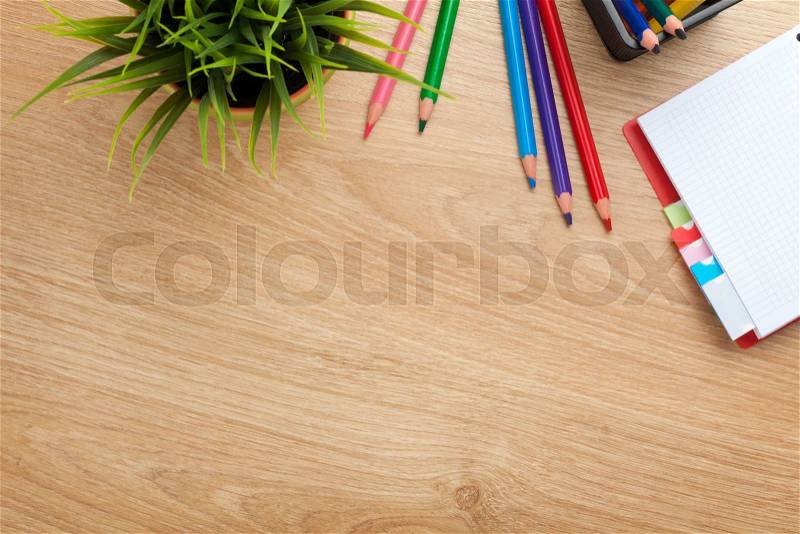 Office table with flower, blank notepad and colorful pencils. View from above with copy space, stock photo