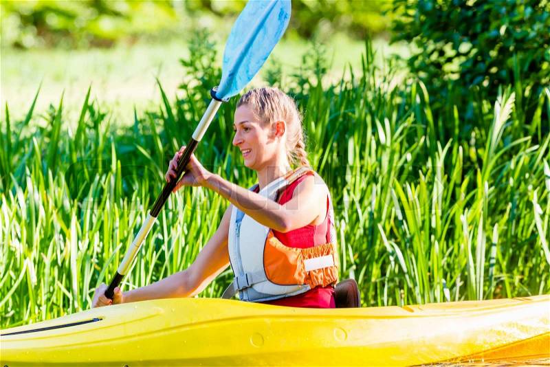 Woman paddling with canoe on forest river, stock photo