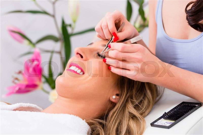 Woman receiving false eye lashes in beauty studio, stock photo