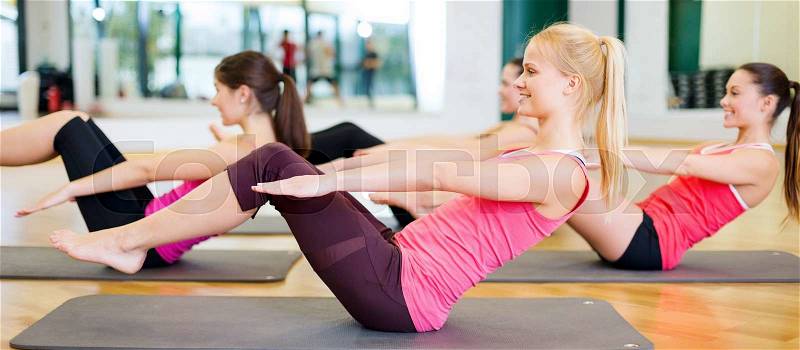 Fitness, sport, training, gym and lifestyle concept - group of smiling women exercising on mats in the gym, stock photo
