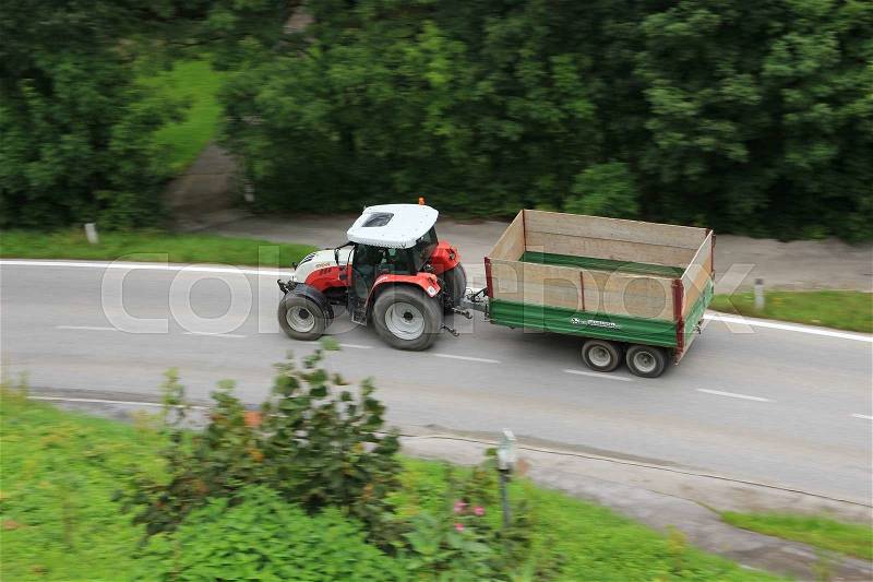 Tractor with an empty trailer driving in the mountains in the summer, stock photo