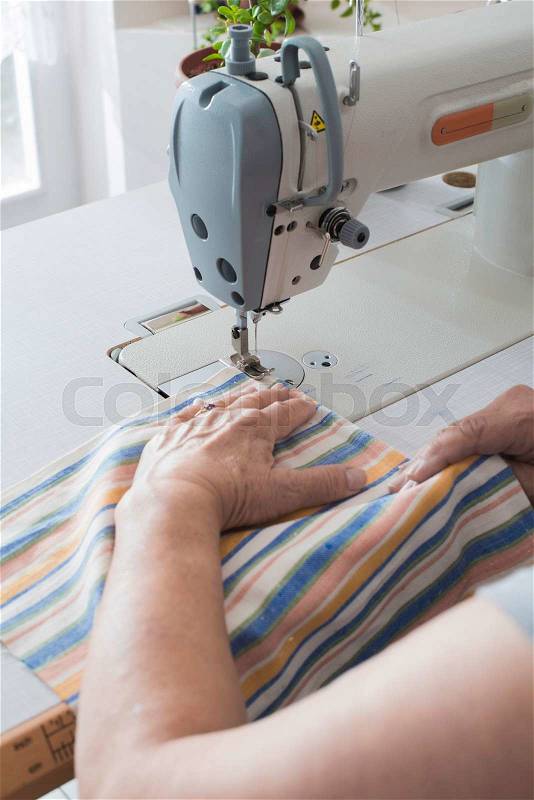 Women sew on sewing machine. White machine, stock photo