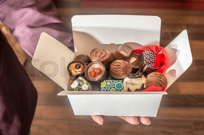Hands holding a box of chocolates. Close up, stock photo