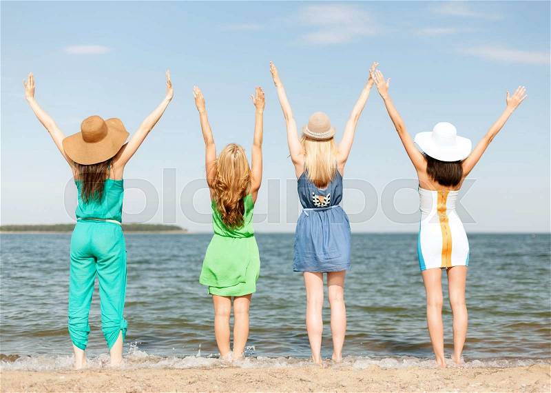 Summer holidays and vacation concept - girls with hands up on the beach, stock photo