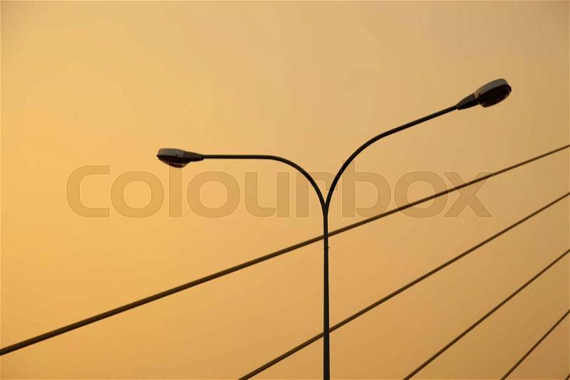 Light pole and rope bridge During the evening, the sun turns orange, stock photo