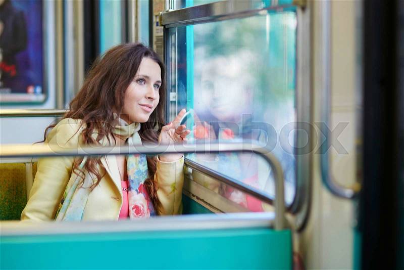 Young beautiful Parisian woman travelling in a subway train, sitting near the window, stock photo