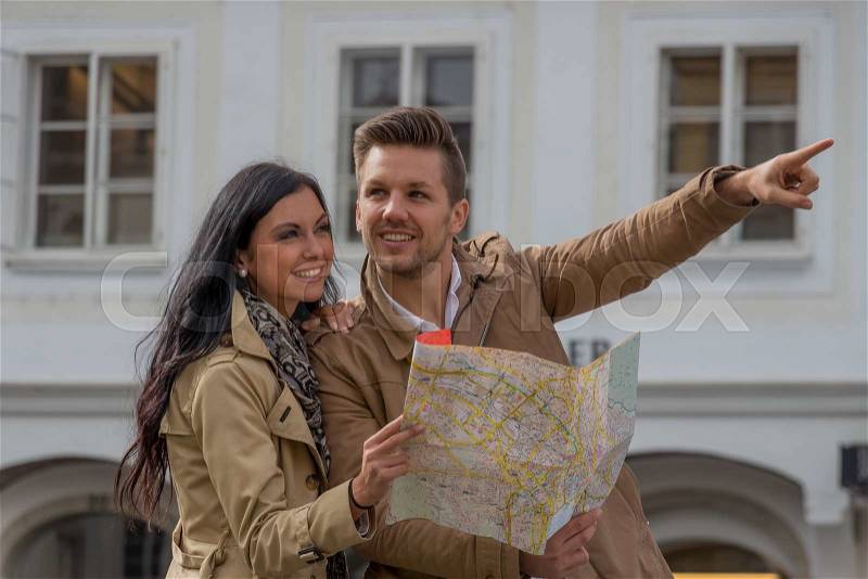 Young couple with map and guide during a tour of town on vacation, stock photo