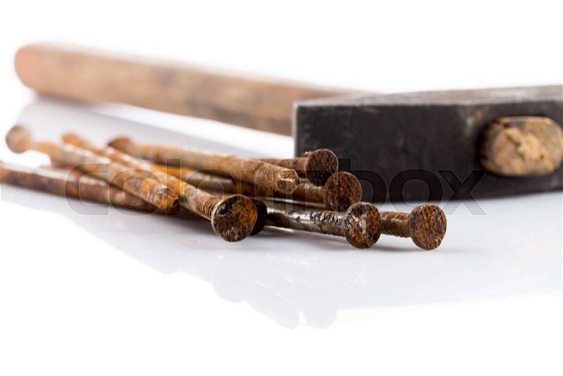 Old hammer with wooden handle and some nails on white table, stock photo