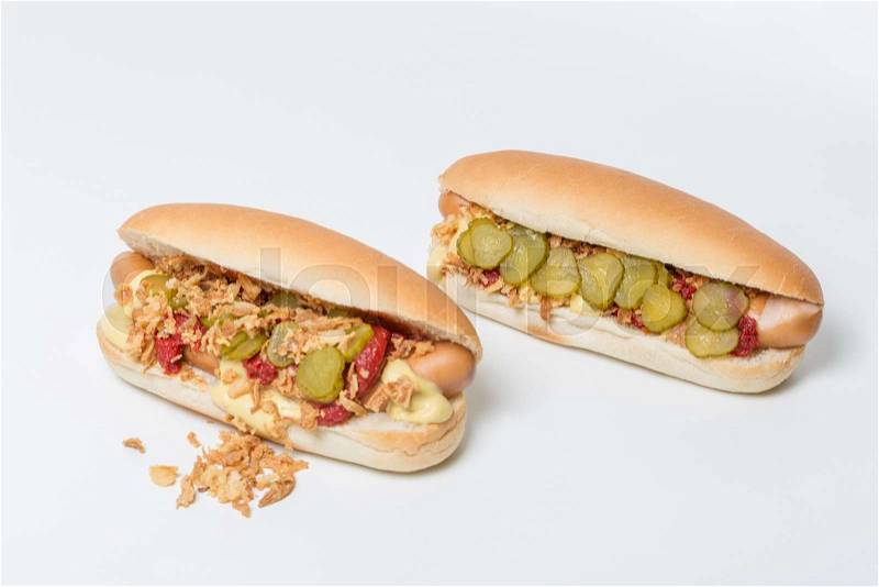 Hot Dog sausage in a bun with roasted onions, pickles, ketchup and mustard on white background, stock photo