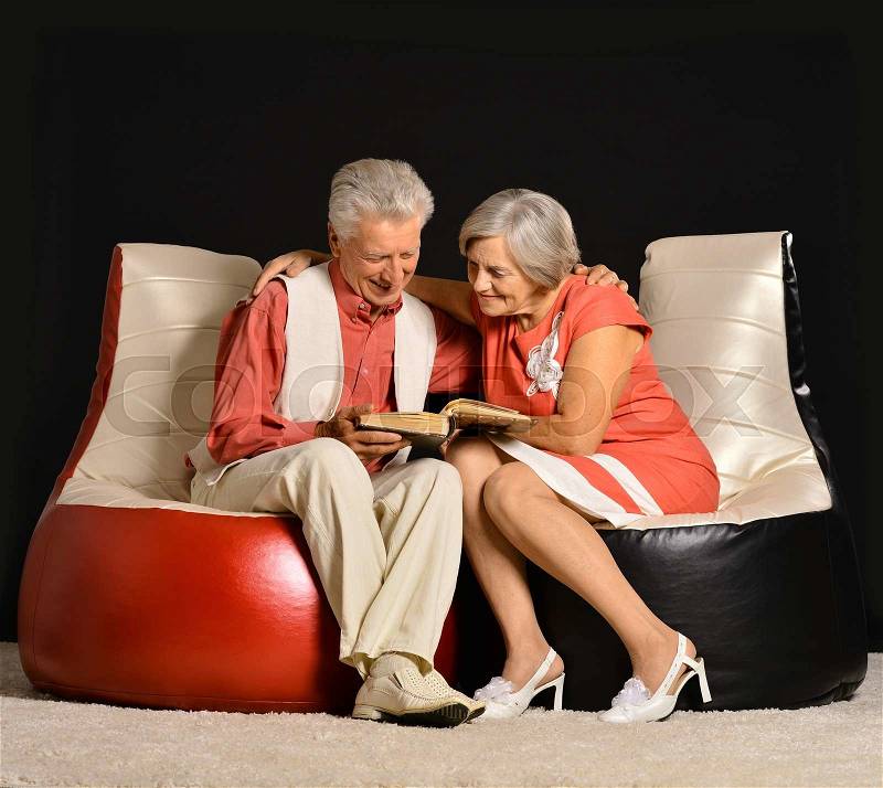 Fashionable elderly couple in studio on black background, stock photo