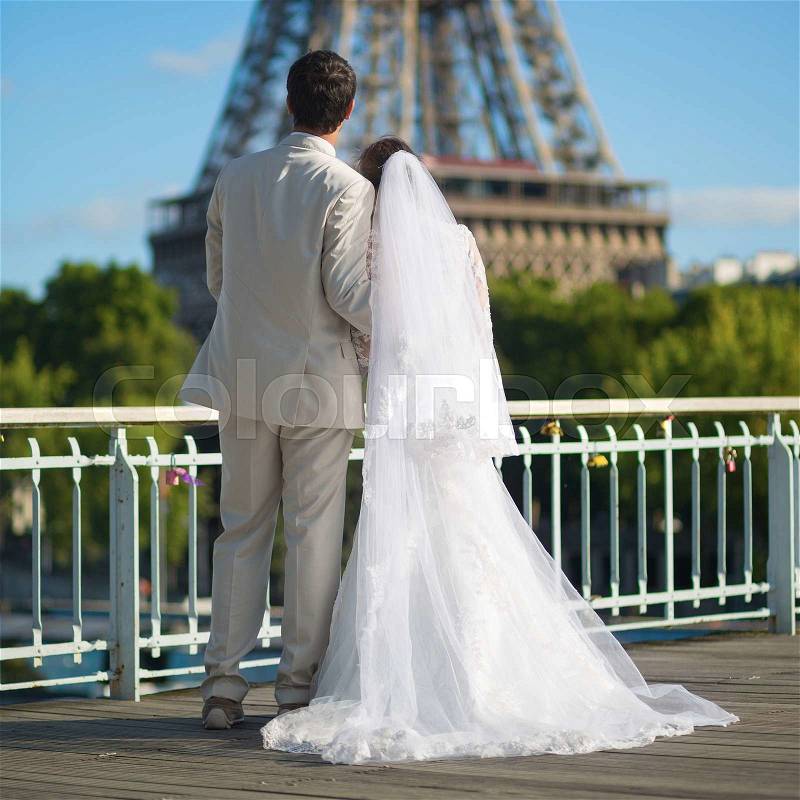 Beautiful just married couple in Paris near the Eiffel tower, stock photo