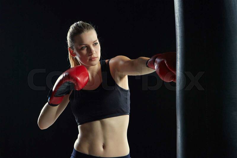 Beautiful woman with the red gloves is boxing on black background, stock photo