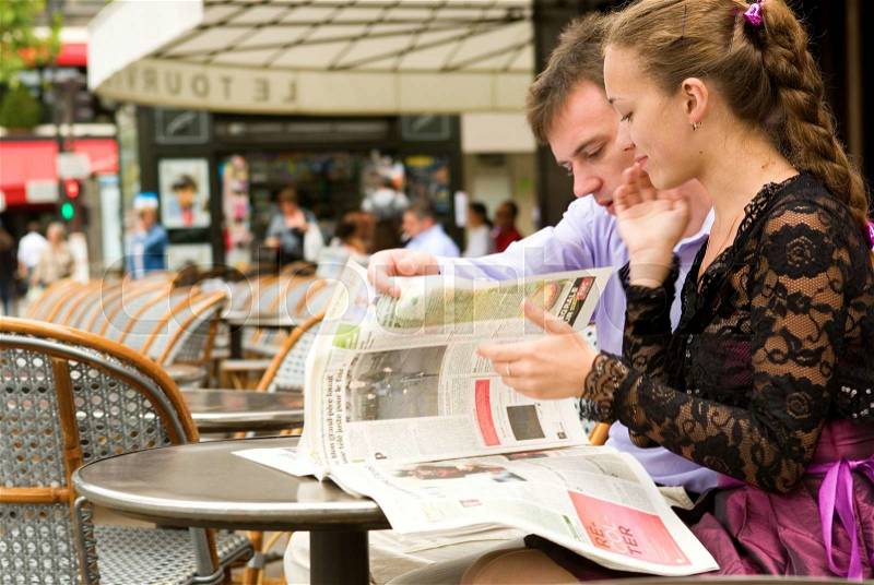 Romantic couple in Paris, reading newspaper in cafe, stock photo