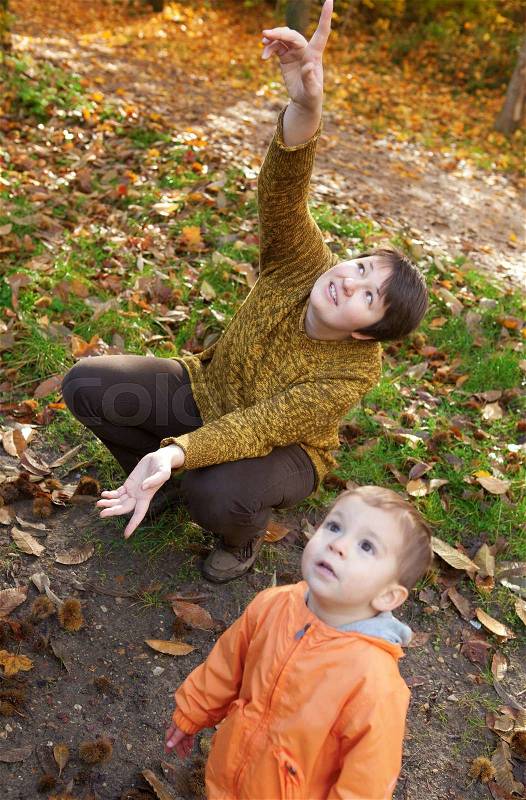 Mother and son in autumn forest, looking at plane in the sky, stock photo