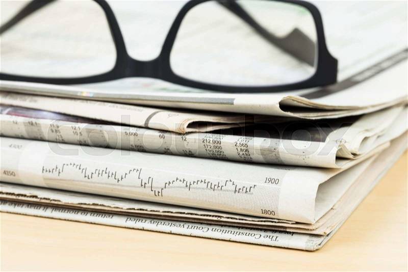 Stack of business newspapers on table with glasses, stock photo