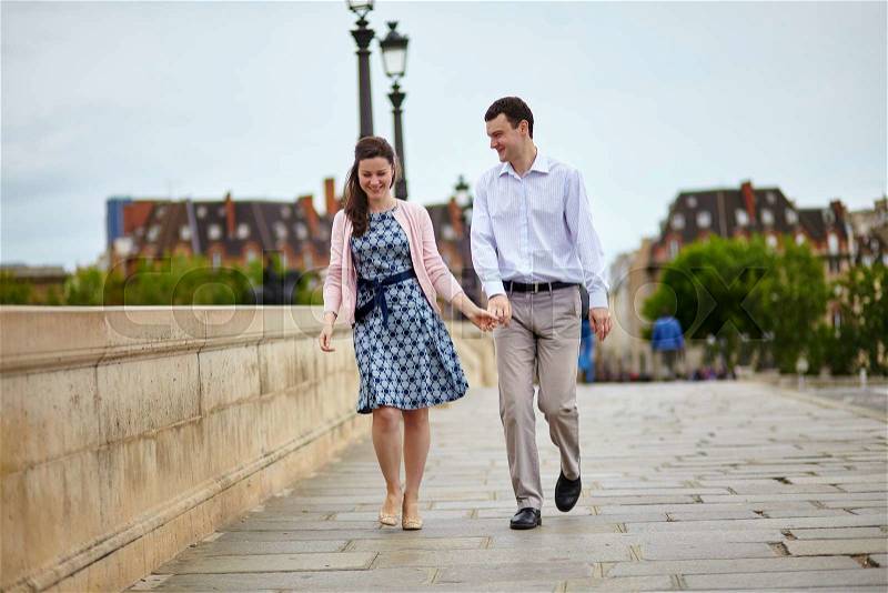Positive dating couple in Paris walking hand in hand, stock photo